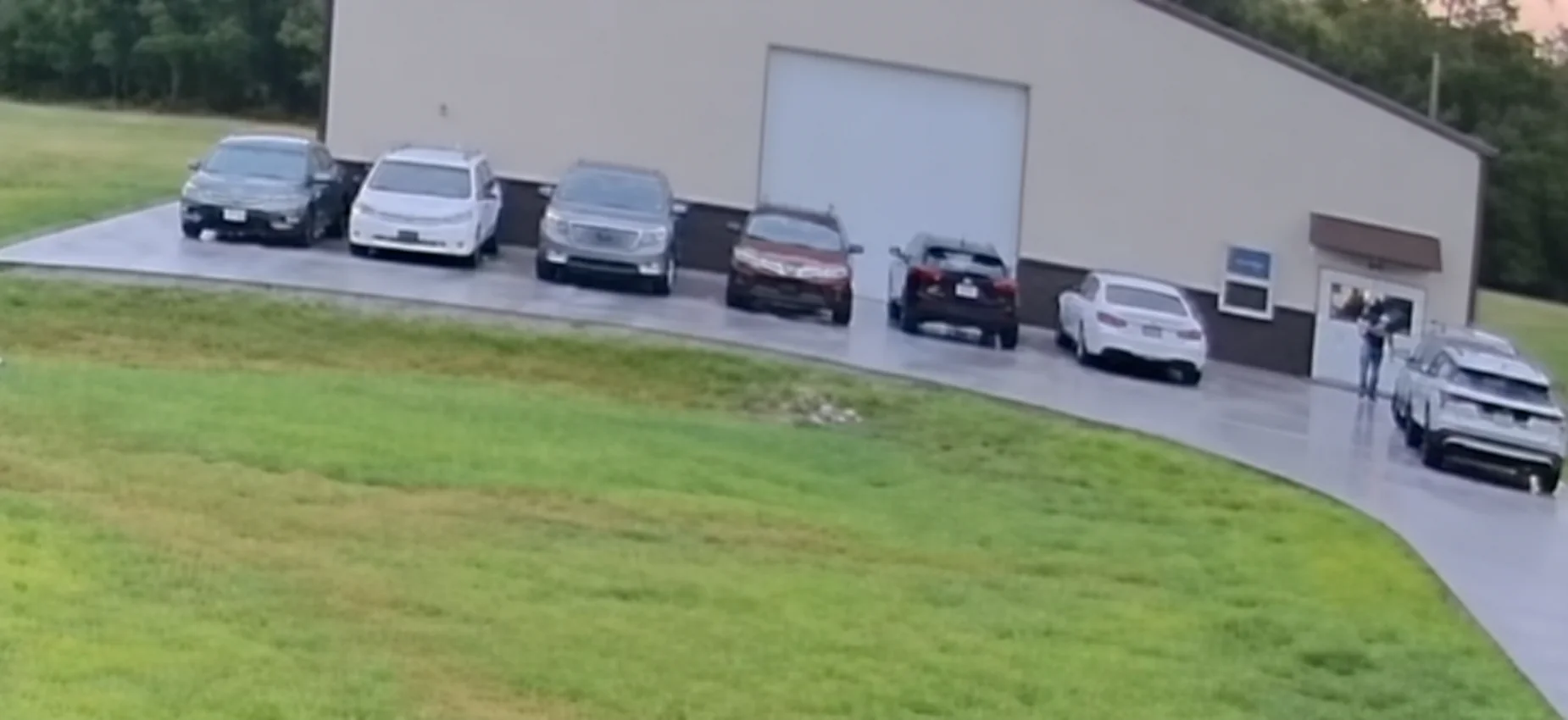 Cars parked in a row on the concrete in front of the barn
