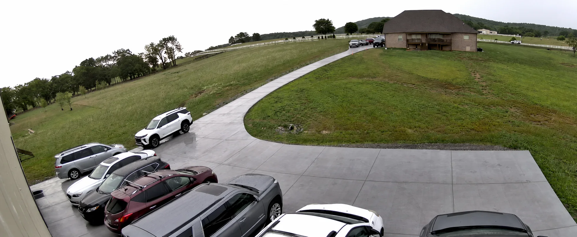 A wider view of cars parked on the concrete by the barn
