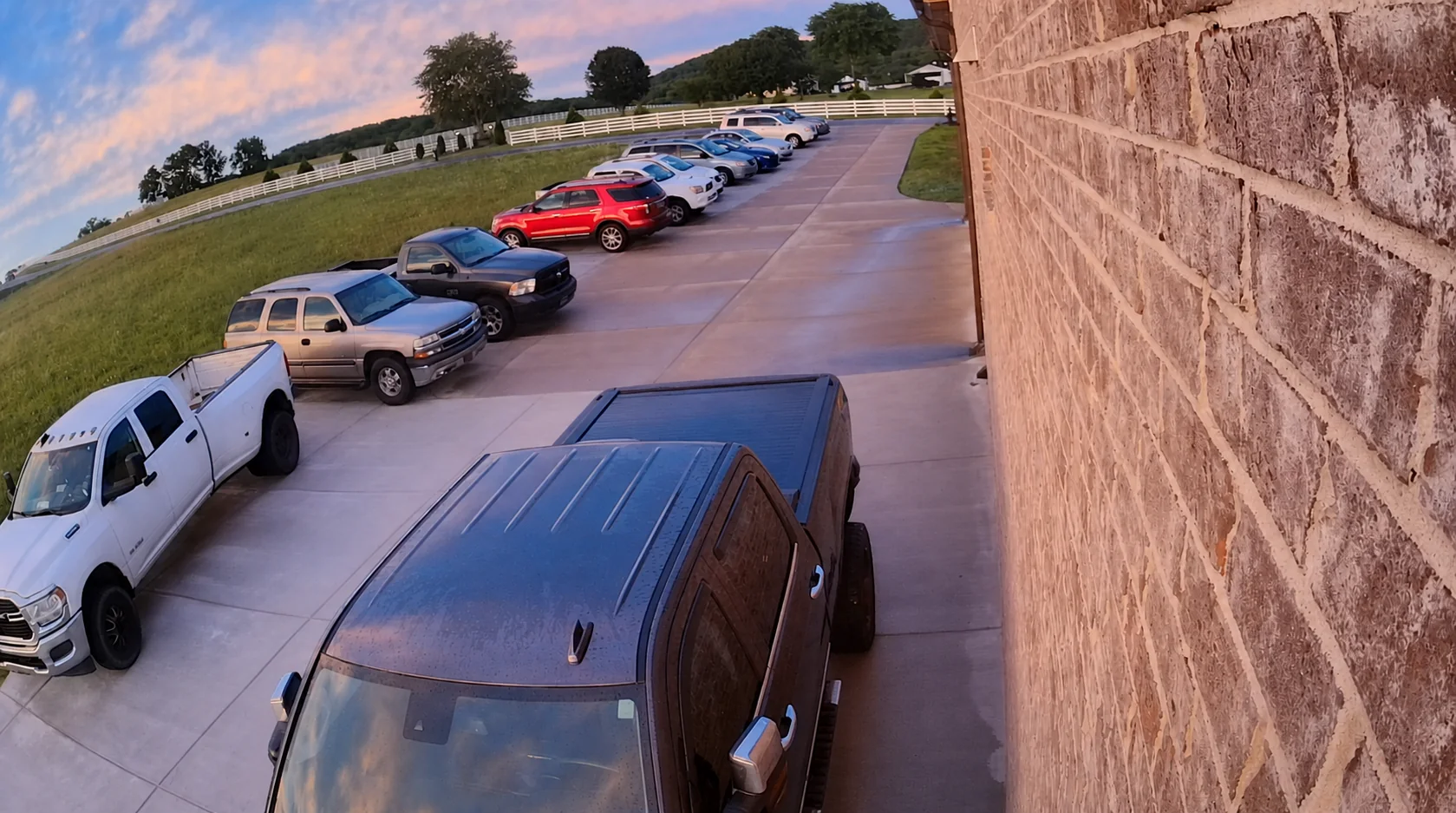 Cars parked along the driveway with additional space next to the brick wall